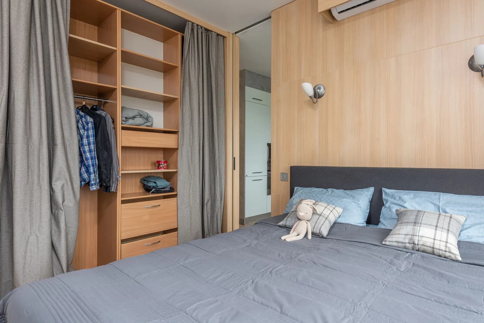 Camera arredata con letto, armadio a vista e ripiani in un monolocale luminoso