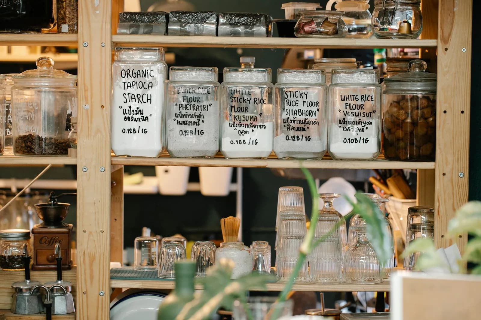 Glass jars of dry food lined up on a wooden shelf