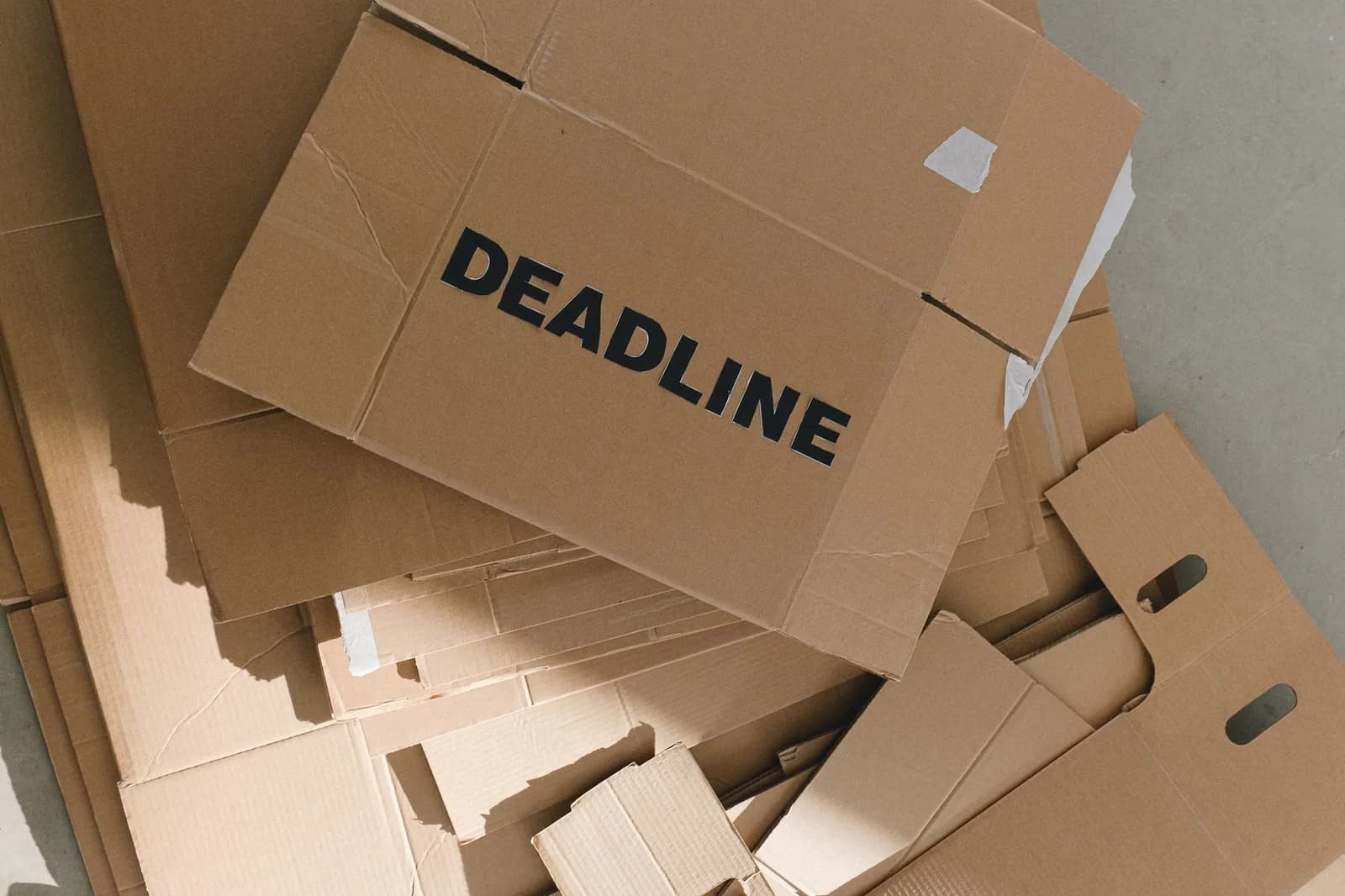 Scatoloni di cartone piegati e ammucchiati, su uno c'è scritto DEADLINE