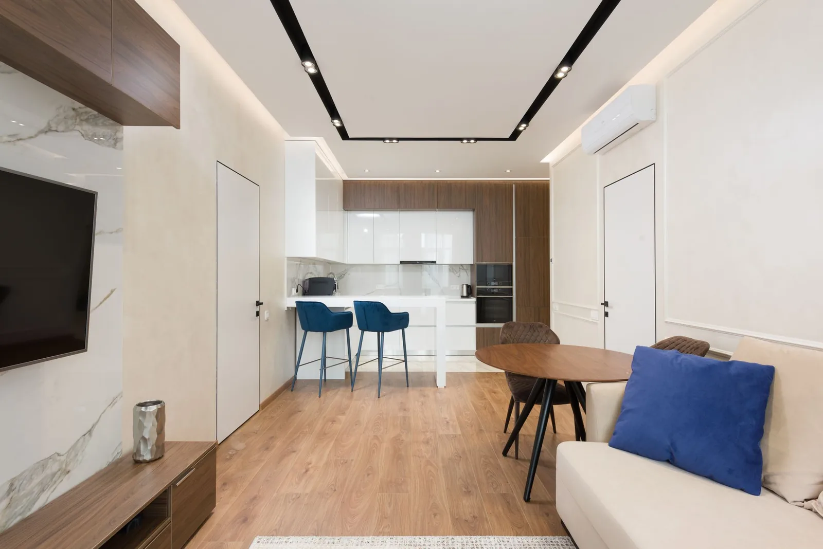 Soggiorno ammobiliato con divano, mobili in legno e zona cucina alle spalle