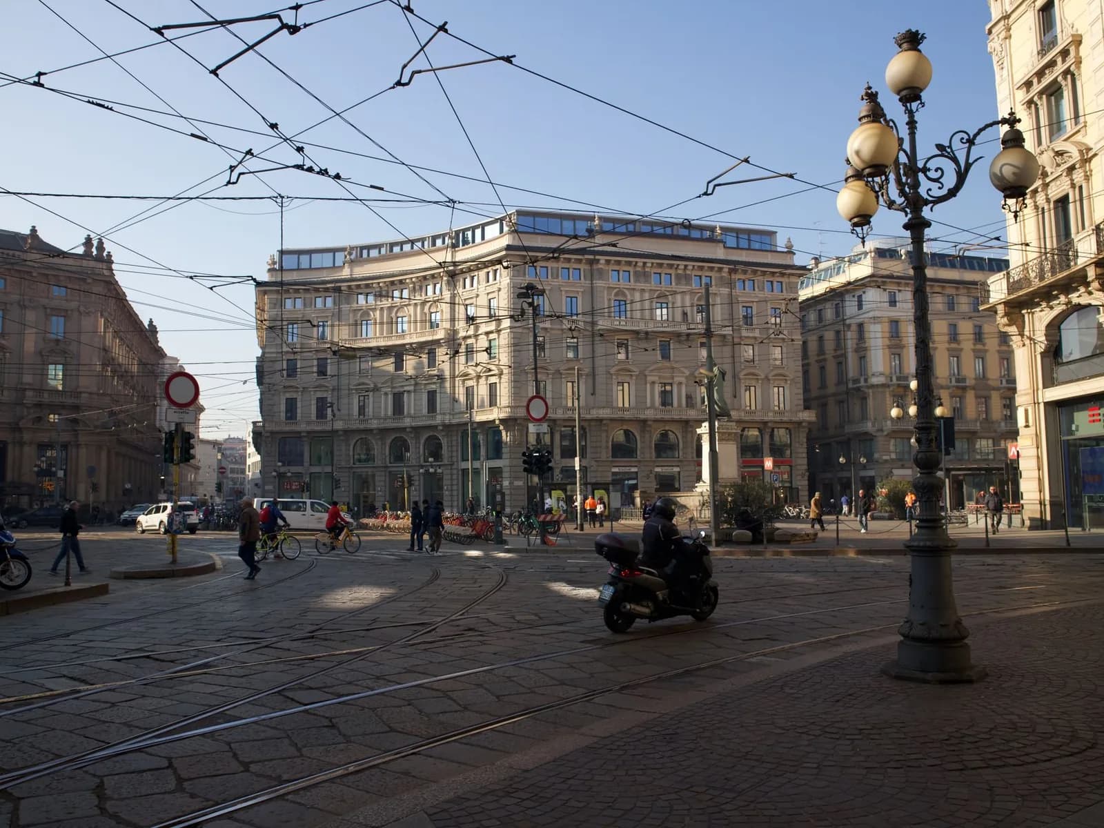 Un incrocio di piazza Cordusio a Milano con motorini e passanti