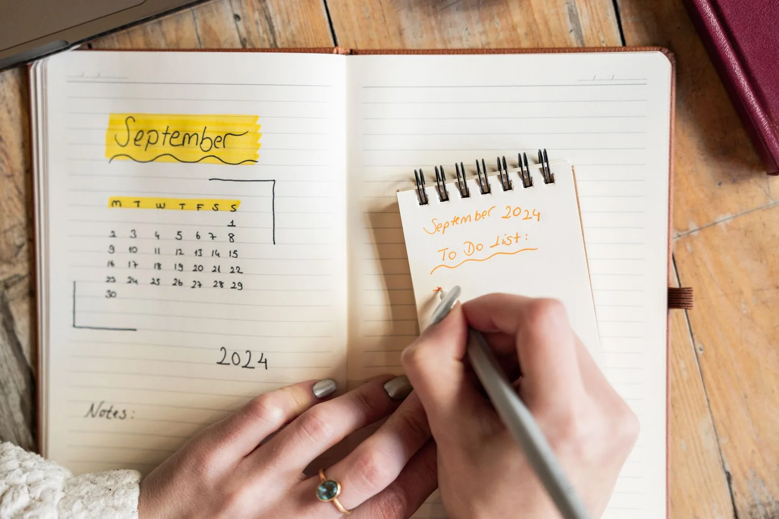 Una donna scrive una lista di cose da fare di settembre su un quaderno
