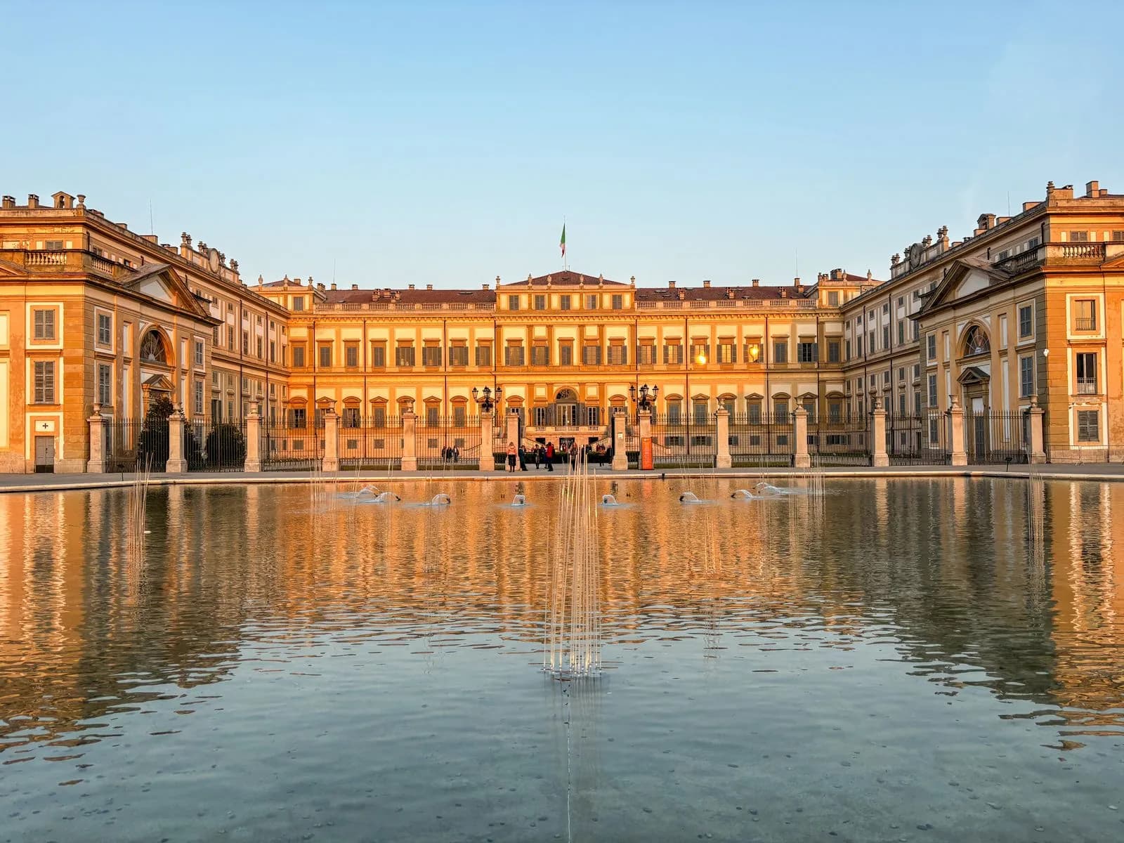 La Villa Reale di Monza riflessa nella vasca davanti alla facciata, al tramonto.