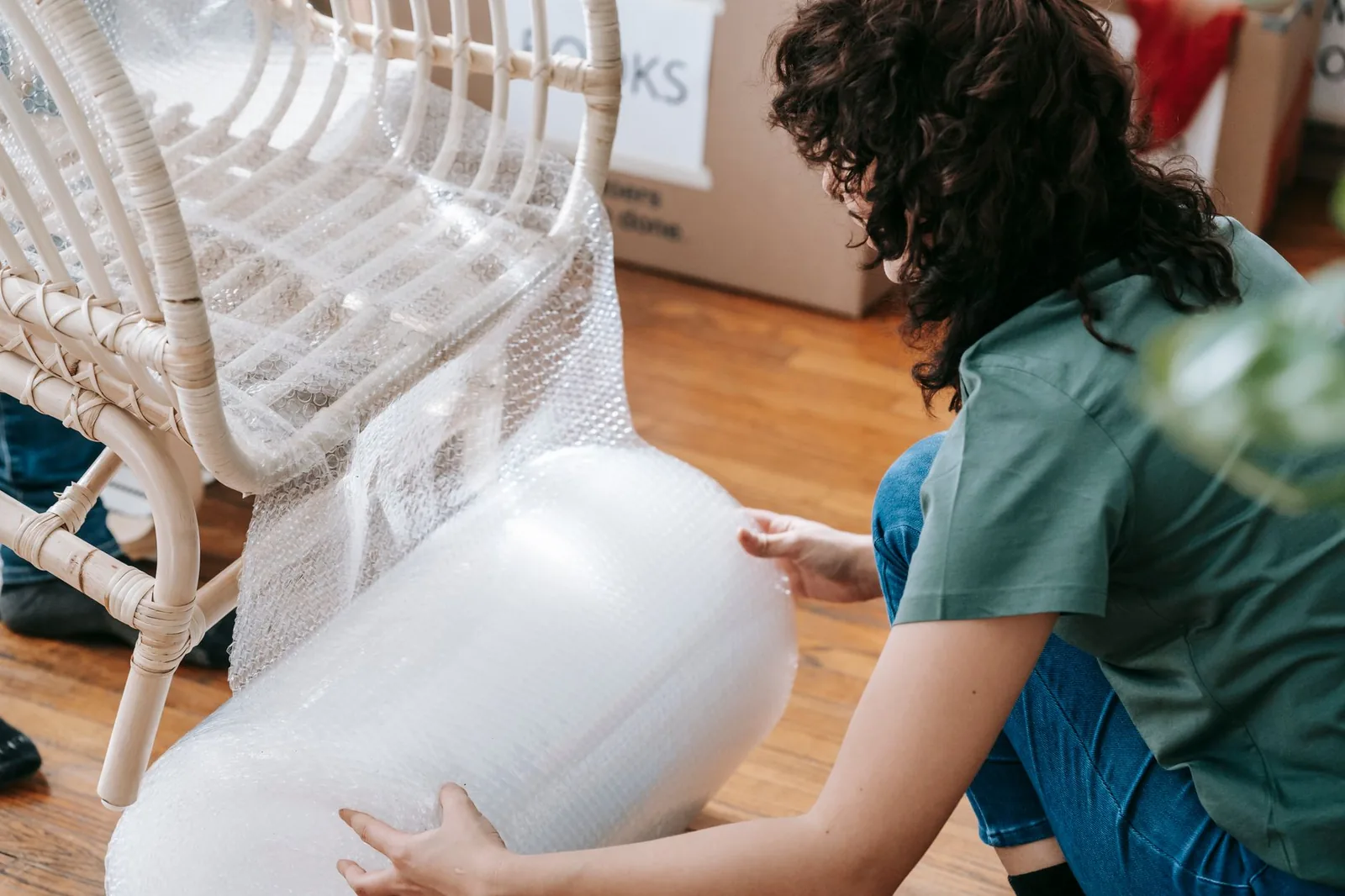 Una sedia in rattan avvolta nella pluriball, accanto a scatoloni etichettati, pronta per essere custodita.