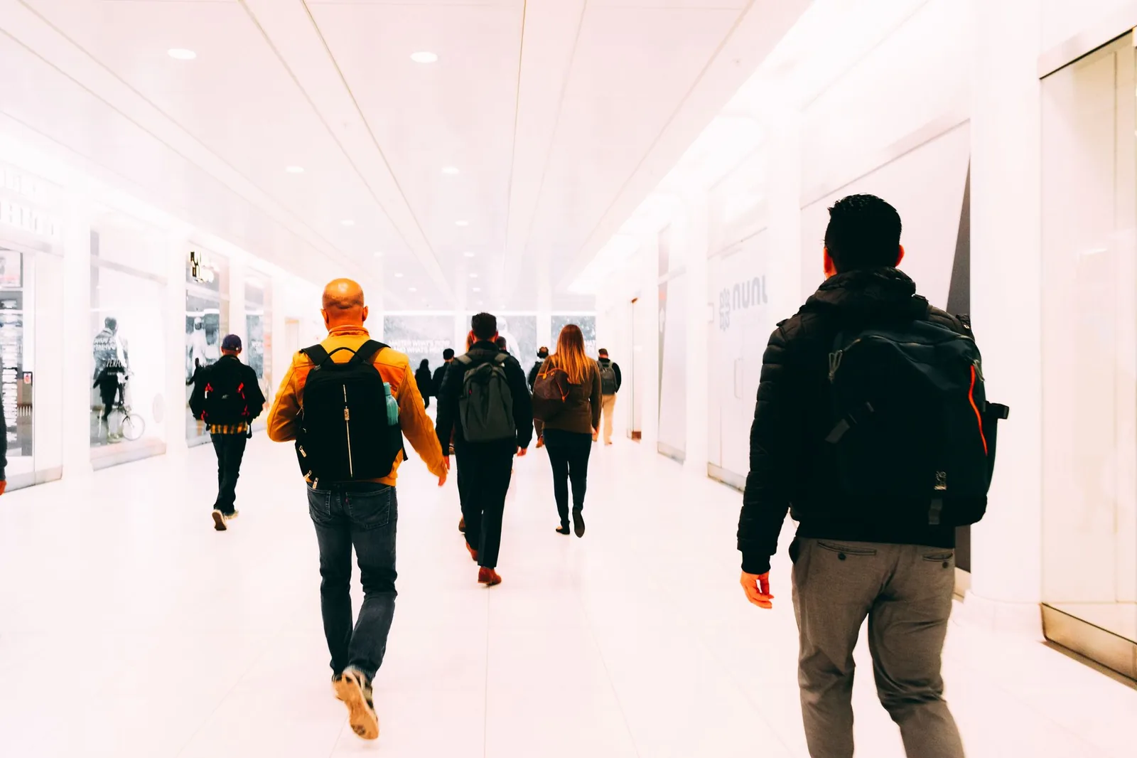 Viaggiatori con lo zaino in spalla attraversano il terminal luminoso di un aeroporto.