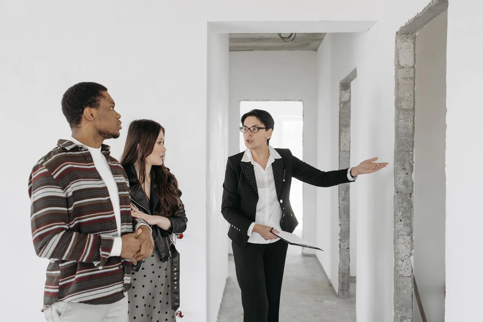Un'agente immobiliare mostra un appartamento vuoto a una coppia di clienti.